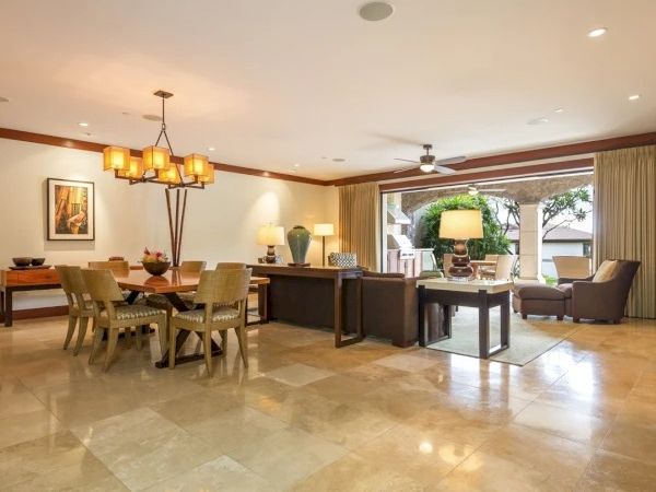 A spacious, well-lit living and dining area with a dining table, chairs, a seating area, and large windows providing natural light, polished marble floors, and warm decor. Top it at 140 characters, ending with a period.