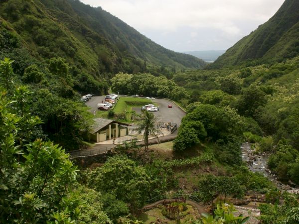 A lush canyon with green hills, a river, and a small patio area or overlook nestled in the valley.