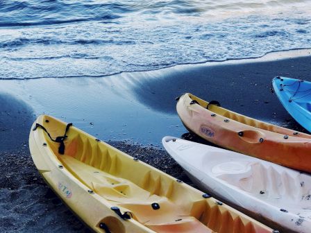 Colorful kayaks on a rocky beach, calm water, and gentle waves at the edge of the shore.