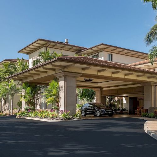 A stylish, tropical-style house with a sloped roof, stone accents, lush greenery, and a warm, inviting entrance. Top it at 140 characters, always ending the sentence.
